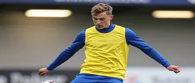 A tight waist-up shot of a 25-year-old Lillestrøm midfielder, dressed in a yellow and blue plain training top, with the...