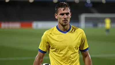 Mid-30s Lillestrøm forward, athletic build, waist-up, intense expression, sweat glistening on brow, wearing a plain...