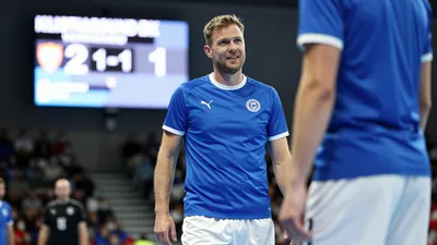A 35-year-old, 5'11" tall, Lillestrøm SK assistant coach with a kind face, wearing a bright blue, smooth polyester...