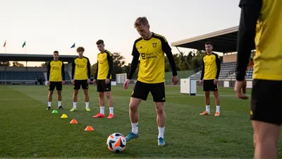 Under overcast summer skies, Stian in Lillestrøm SK's home kit, stands confidently on lush green grass, with blurred...